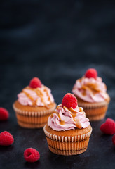 Raspberry and caramel cupcakes on dark background