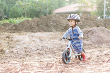 Fototapeta premium Asian boy about 1 year and 9 months is riding baby balance bike on muddy construction road