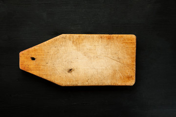 Empty wooden cutting board on a black background, top view