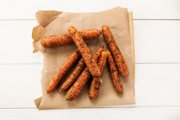 Unwashed fresh carrot on a piece of craft paper top view