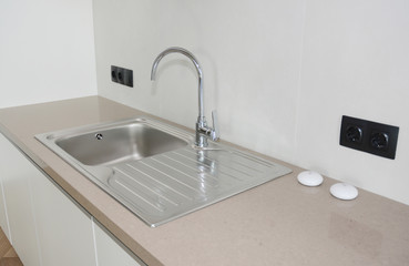 Modern kitchen metal faucet and ceramic kitchen sink.