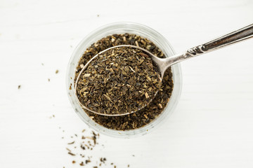 Tea in a glass dish with metal spoon top view