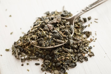 Fototapeta premium Dry tea in a metal spoon on a white wooden table