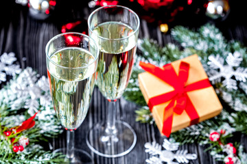 glasses of champagne and Christmas ornaments on dark wooden back