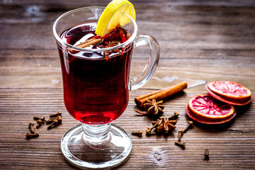 mulled wine with spices in cup on wooden background