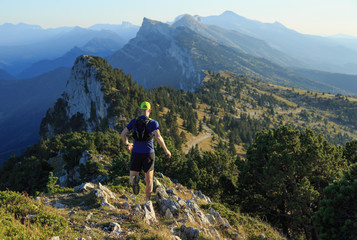 Athlete trail running down the mountains on a beautiful afternoon.
