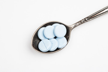 Medications in a metal spoon on a white background