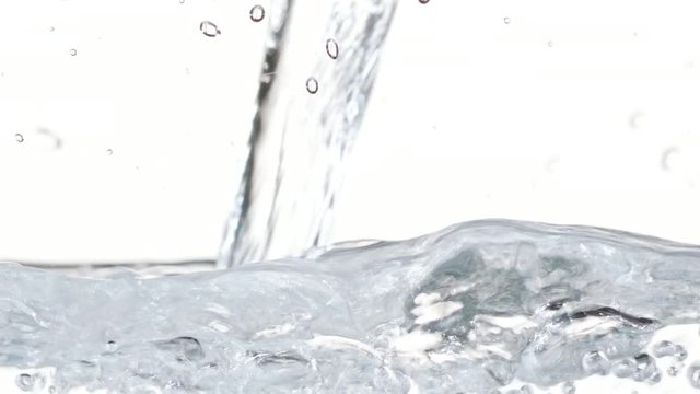Macro footage of water pouring in a transparent container. White background. Close-up macro shot.