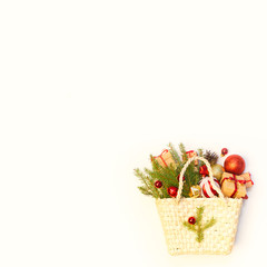 Christmas or New Year background: basket or braided bag with colored glass toys and balls, fir tree branches, decoration and gifts on white background. Selling in the store.