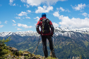 Obraz premium Adventurer, with backpack, stands on the mountain top