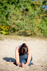 Woman practicing yoga in the sand - Extended Side Angle Pose — Utthita Parsvakonasana - Autumn day