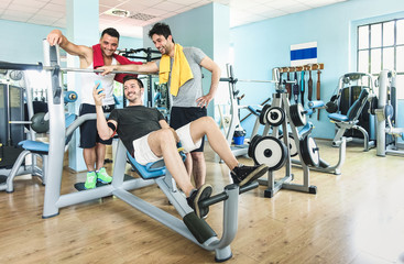 Fototapeta na wymiar Group of sportive friends using mobile phone at gym fitness club - Happy sporty people in weight room training - Social gathering concept in sport lifestyle context - Main focus on guys interaction