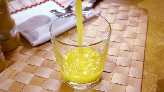 Orange juice pouring into a glass, the morning Breakfast. Slow motion with rotation tracking shot.