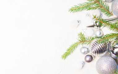 Christmas or New Year background: silver glass toys and balls, fir tree branches, decoration on white background. 