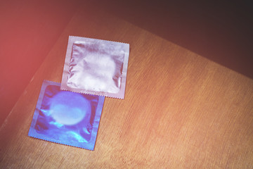 two condoms, one white and one blue, on a wooden surface.