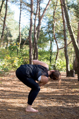 Woman practicing yoga in the sand - Chair pose Twist - Utkatasana - Autumn day