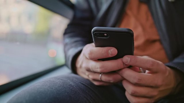 A young man using a smartphone on the bus. Close-up shot. Soft focus.