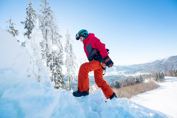 Fototapeta na wymiar Snowboarder carrying his board walking in the winter mountains on sunny day copyspace active sports lifestyle recreation people