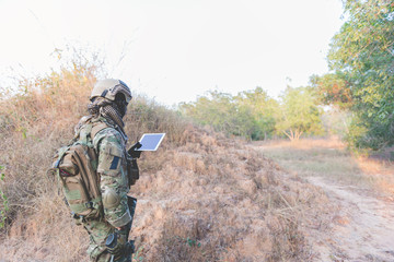 Soldier using map on tablet for orientation at forest