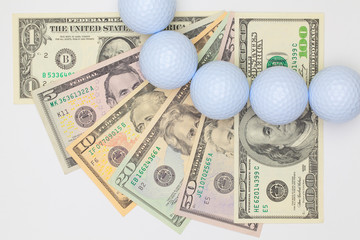 White golf balls and different us dollar banknotes.