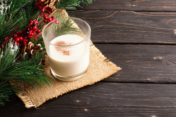 Glass of eggnog on wooden background