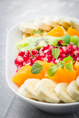 Winter fruit salad with healthy mint and honey dressing on stone, concrete background.Selective focus, close up. 