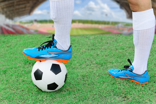 Feet of soccerman with football stud on ball at soccer field