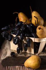 Autuimn grapes and pears in a box in low key light