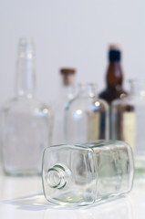Vintage clear glass liquor bottles with one on its side with plain background