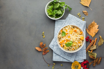 The perfect vegetarian dinner. Bulgur with pumpkin, carrots, spices (ginger, cinnamon, pepper, cardamom), honey and cilantro. A autumn gray concrete background for you.  Flat lay, top view
