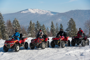 Group of people driving quad bikes on snow at top of the mountain in winter © anatoliy_gleb