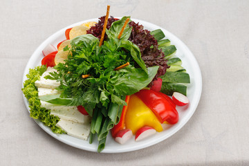 Freash vegetables and sheep cheese decorated with parsley and dill on a white plate