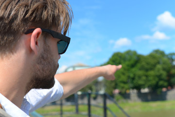 Man looking aside and pointing far. Guy with sunglasses