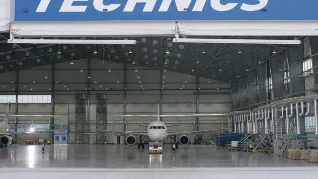 Aircraft in the technical hangar. Airplane parking in hangar. Airplane arrives at the hangar of the airport. Boeing