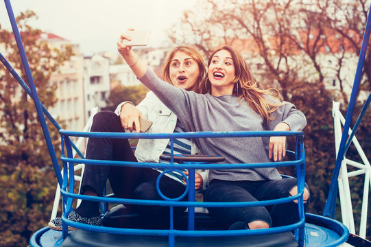 Two girls taking selfie while having fun in amusement park