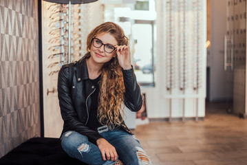 Beautiful woman with new glasses in optical store.