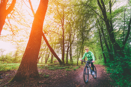 MTB Cyclist in the forest sunlight.Young man riding a mountain bike through the woods.