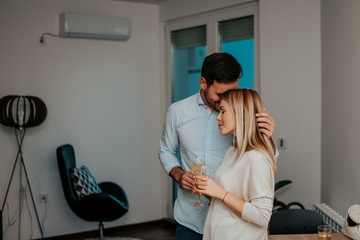 Young couple in living room hugging.