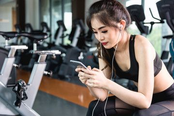 Fototapeta premium Active girl using smartphone in fitness gym.