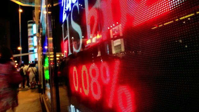 Pedestrians walk past a financial display board in Hong Kong