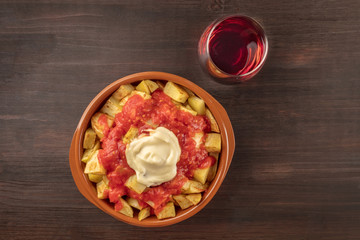 Overhead photo of patatas bravas with wine and copyspace
