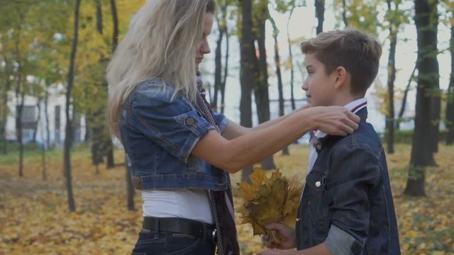 Mother prepares son for school and straighten his collar of shirt