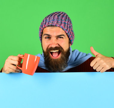 Man in hat holds cup on green and cyan background