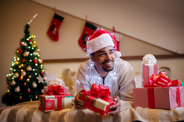Happy afro american with christmas hat and presents around.