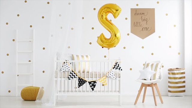 Fully furnished cute baby room with crib and big golden balloon