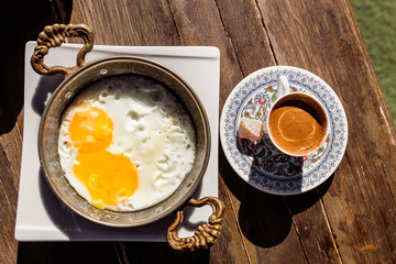 romantic turkish breakfast with fried eggs and coffee on table in cafe
