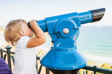Baby girl looking through a paid telescope