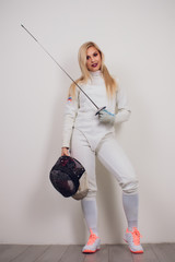 woman wearing fencing suit practicing with sword against grey vignette