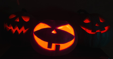 Scary Halloween pumpkins on a black background. Halloween card concept. Spooky glowing faces