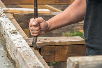 Worker with a crowbar when stripping a wood-clad concrete wall
